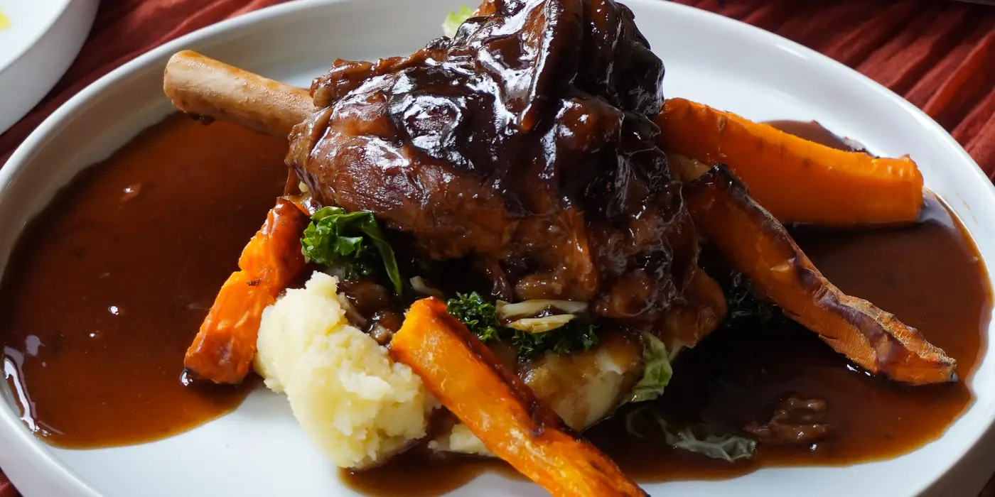 Photo of a Lamb Shank with gravy, carrots and mash.
