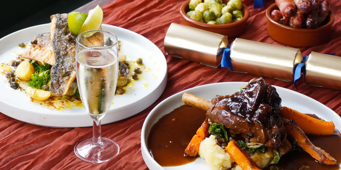 Photo of the Baked Sea Bass and the Lamb Shank with bowls of sides in the background